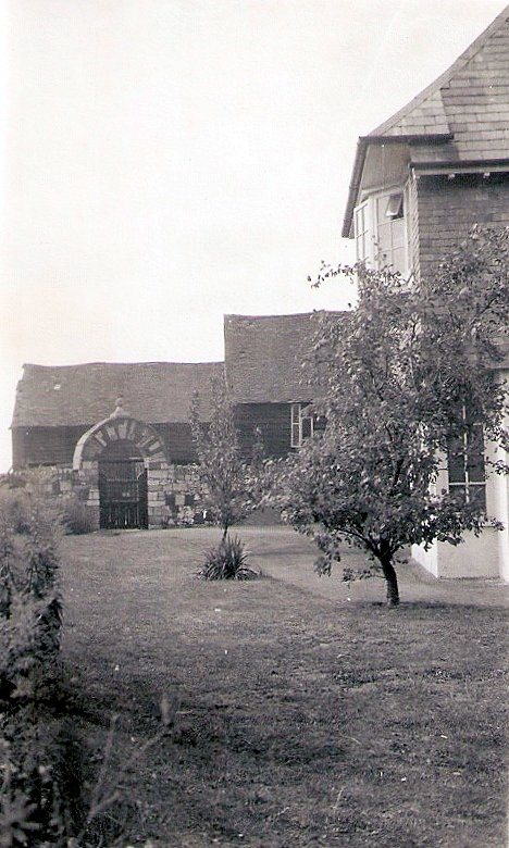 Front garden of the farmhouse with outbuildings in the background.