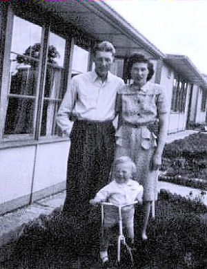 A family in front of a Rd Prefab