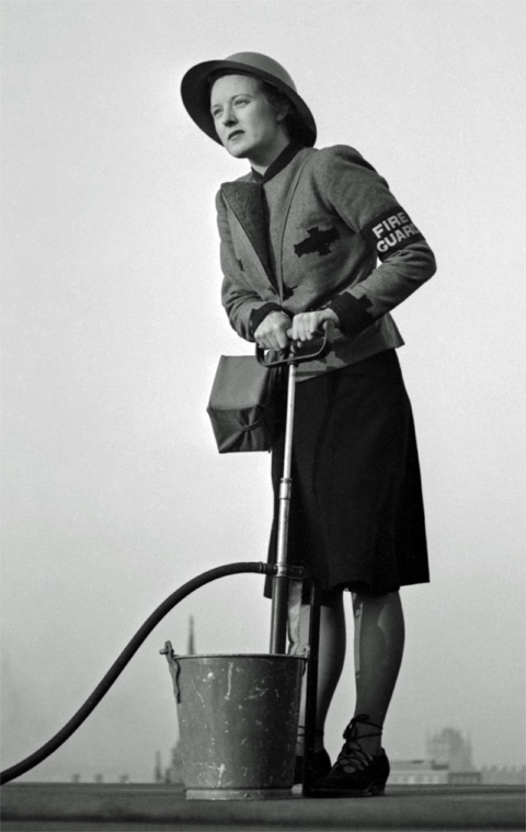 A female Fire Guard using a stirrup pump on the roof of a building in London, 1941 A female Fire Guard using a stirrup pump on the roof of a building in London, 1941
